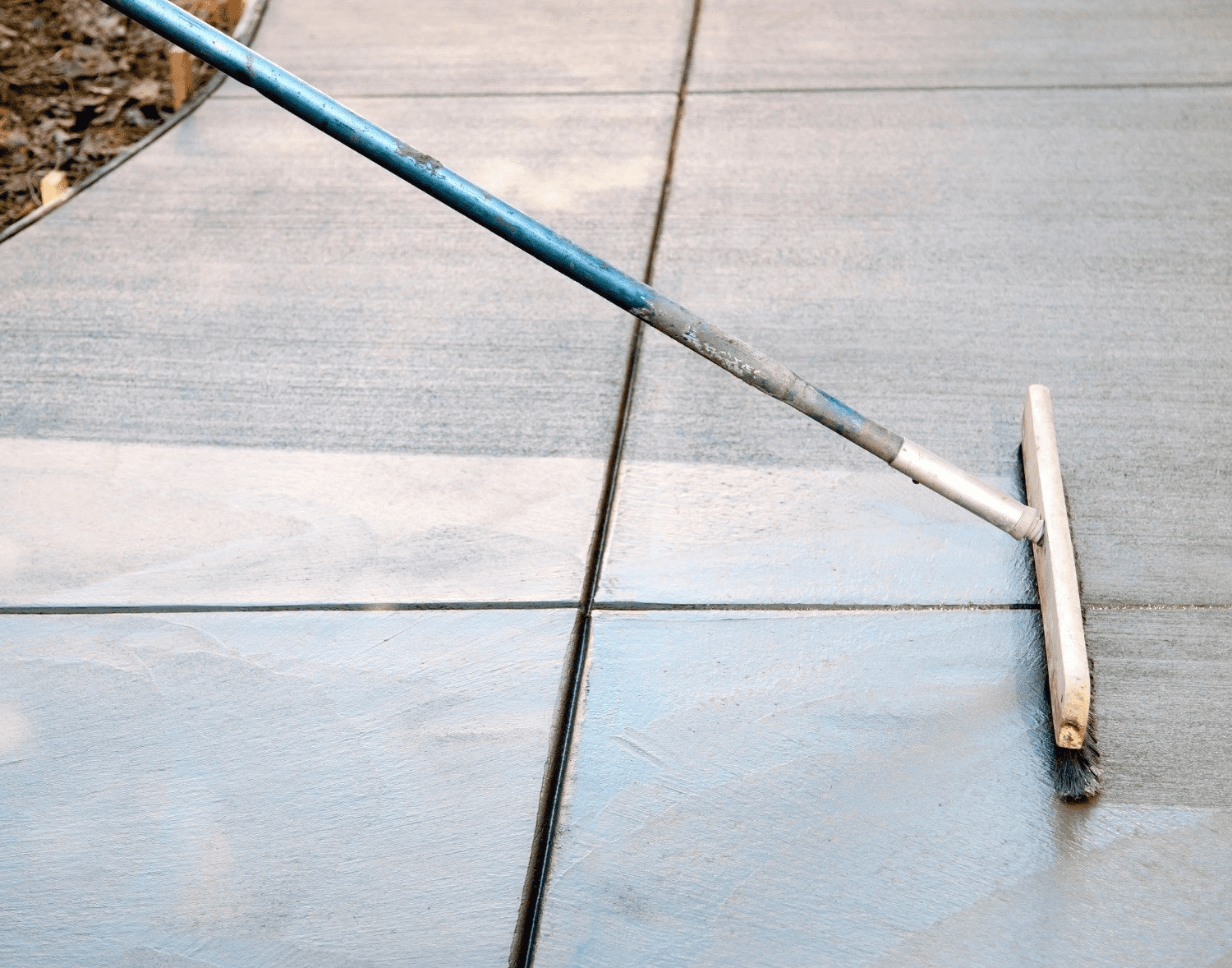 a horsehair broom is used to level the newly resurfaced walkway in Naples Manor
